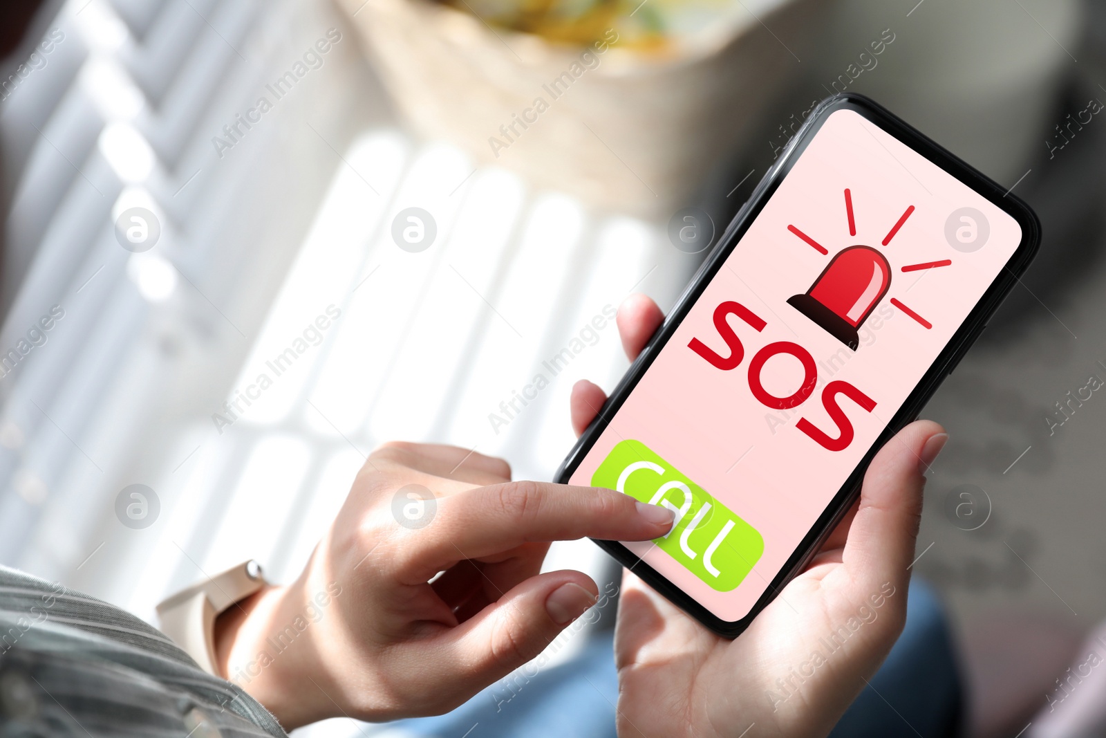 Image of Woman holding smartphone with emergency call SOS on screen indoors, closeup