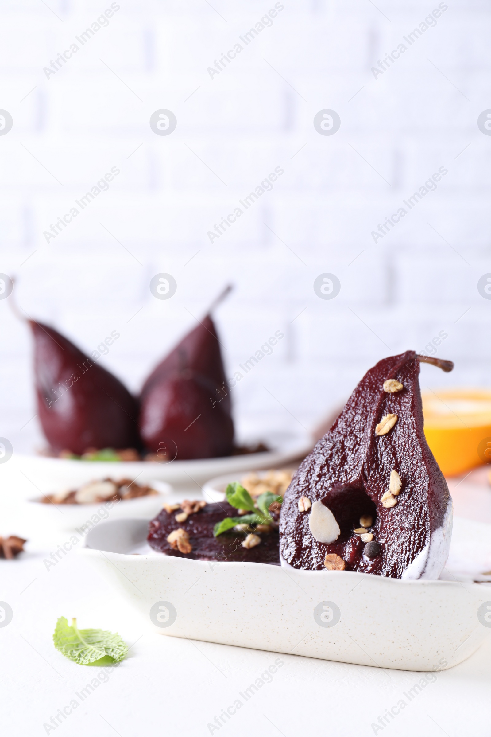 Photo of Tasty red wine poached pears with muesli in bowl on white table, closeup