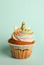 Photo of Cute sweet unicorn cupcake on light turquoise background