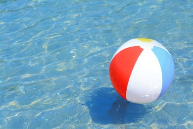 Colorful beach ball floating in sea on sunny day, space for text