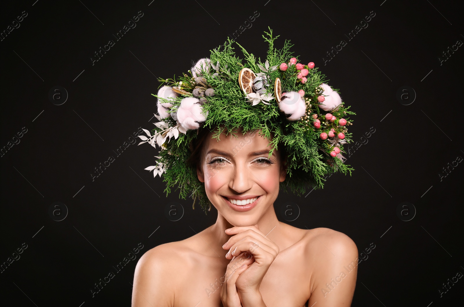 Photo of Happy young woman wearing wreath on black background