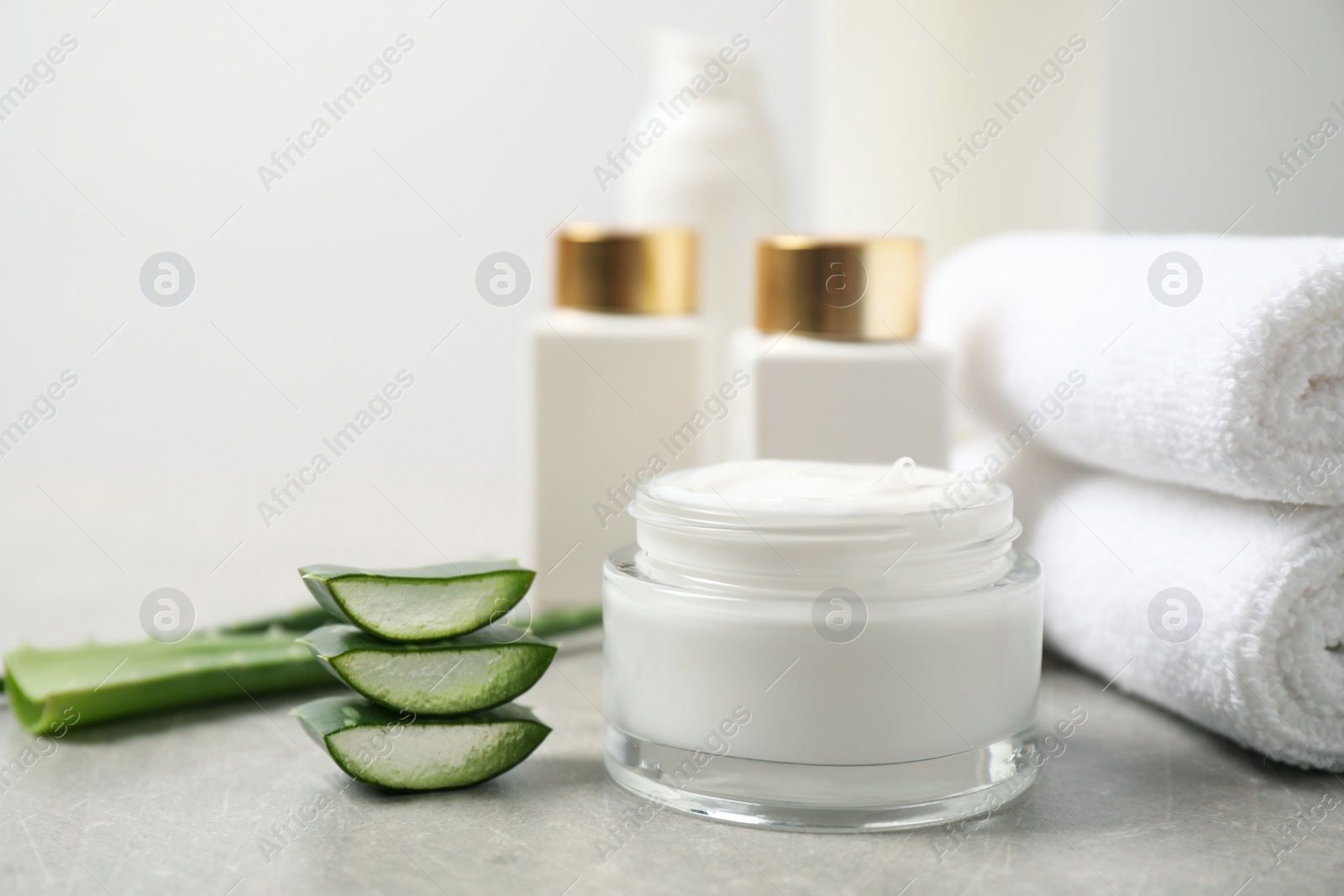 Photo of Different cosmetic products, towels and aloe on grey table