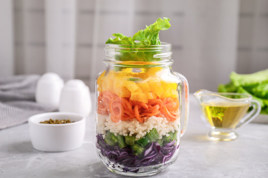 Photo of Healthy salad in glass jar on marble table