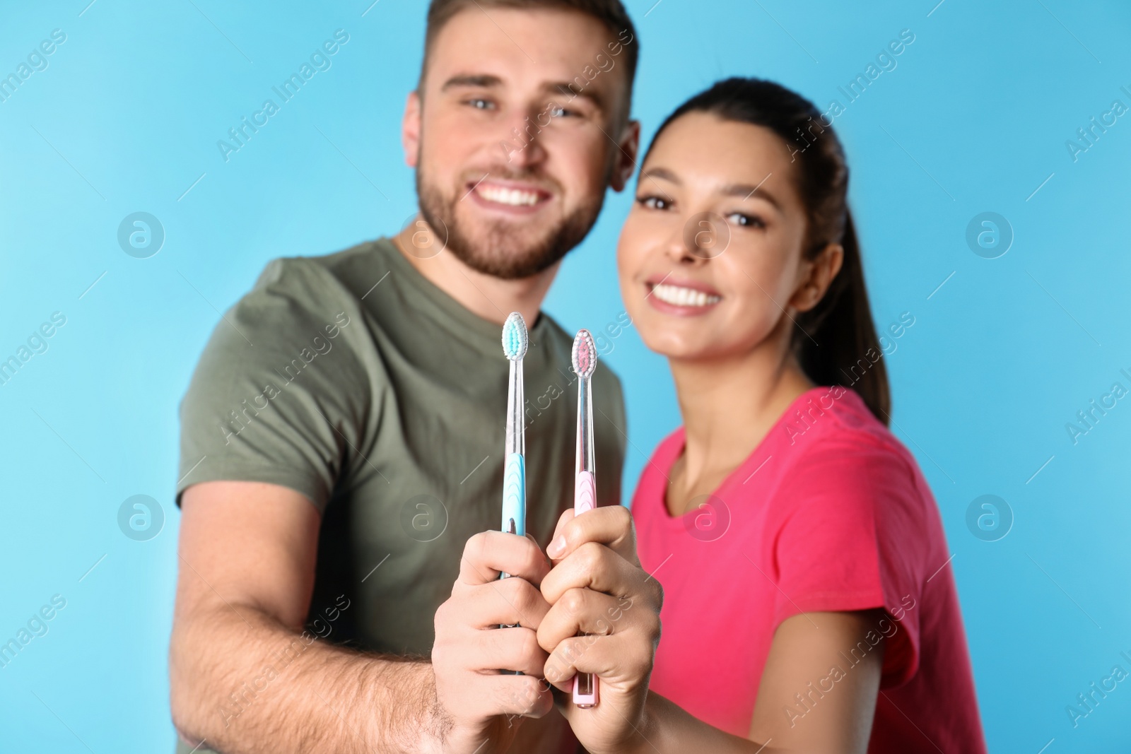 Photo of Young couple with toothbrushes on color background. Teeth care