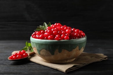 Tasty ripe cranberries on black wooden table, closeup