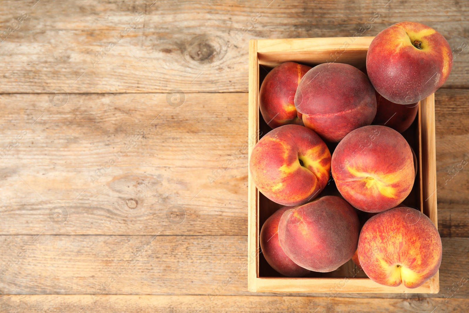 Photo of Crate with tasty peaches on wooden table, top view. Space for text