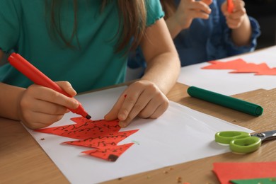 Photo of Little children making beautiful Christmas greeting cards at wooden table, closeup