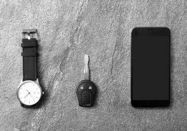 Wristwatch, smartphone and car key on grey background, top view. Space for text