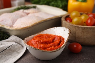 Photo of Fresh marinade, raw chicken and tomatoes on brown table, closeup