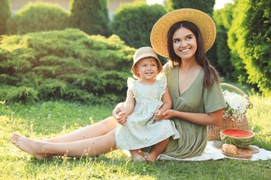 Mother with her baby daughter having picnic in garden on sunny day