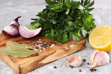 Photo of Bunch of fresh parsley, lemon, onion, garlic and spices on grey textured table