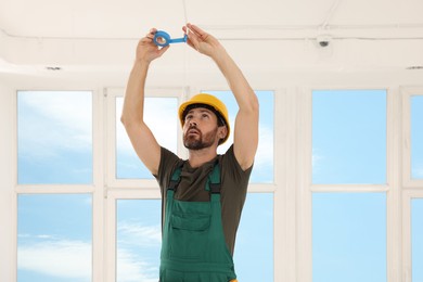 Photo of Electrician fixing wires with insulating tape indoors