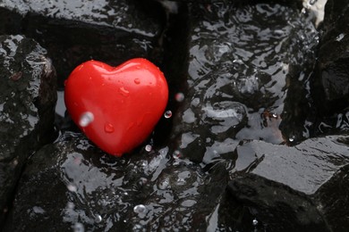 Red decorative heart on stones and water, top view. Space for text