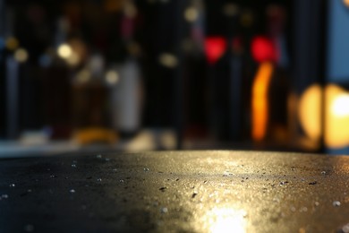 Photo of Empty dark grey table with water drops against blurred background, closeup. Space for text