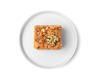 Piece of layered honey cake with walnuts on white background, top view