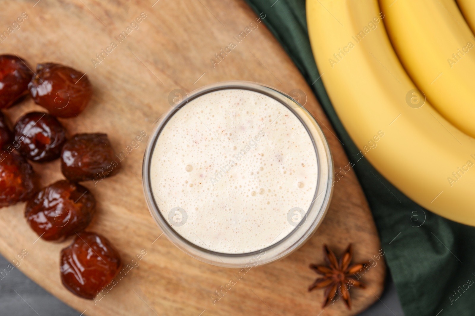Photo of Glass of delicious date smoothie, dried fruits, anise and bananas on table, flat lay
