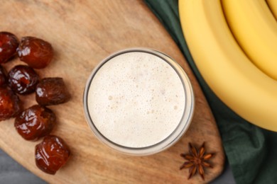 Glass of delicious date smoothie, dried fruits, anise and bananas on table, flat lay