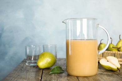 Photo of Fresh pear juice in glass jug and fruits on wooden table