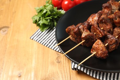 Photo of Delicious shish kebabs with vegetables on wooden table, space for text