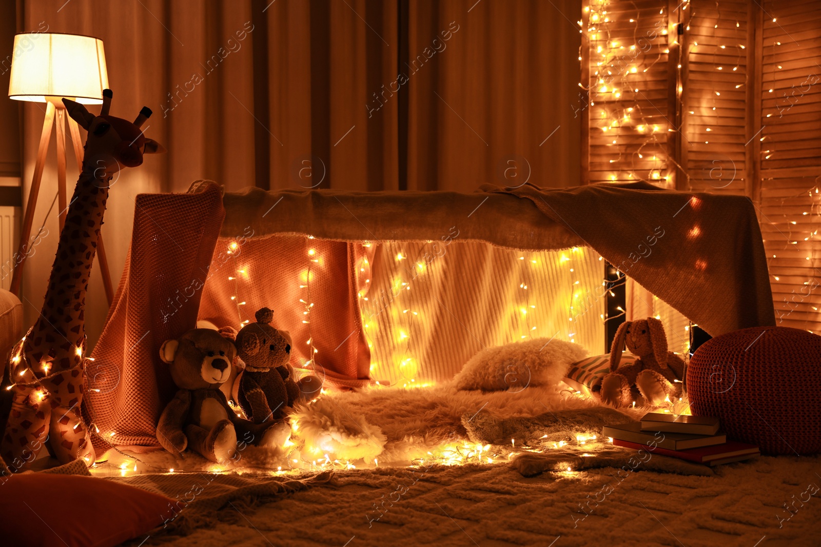 Photo of Beautiful play tent decorated with festive lights and toys at home