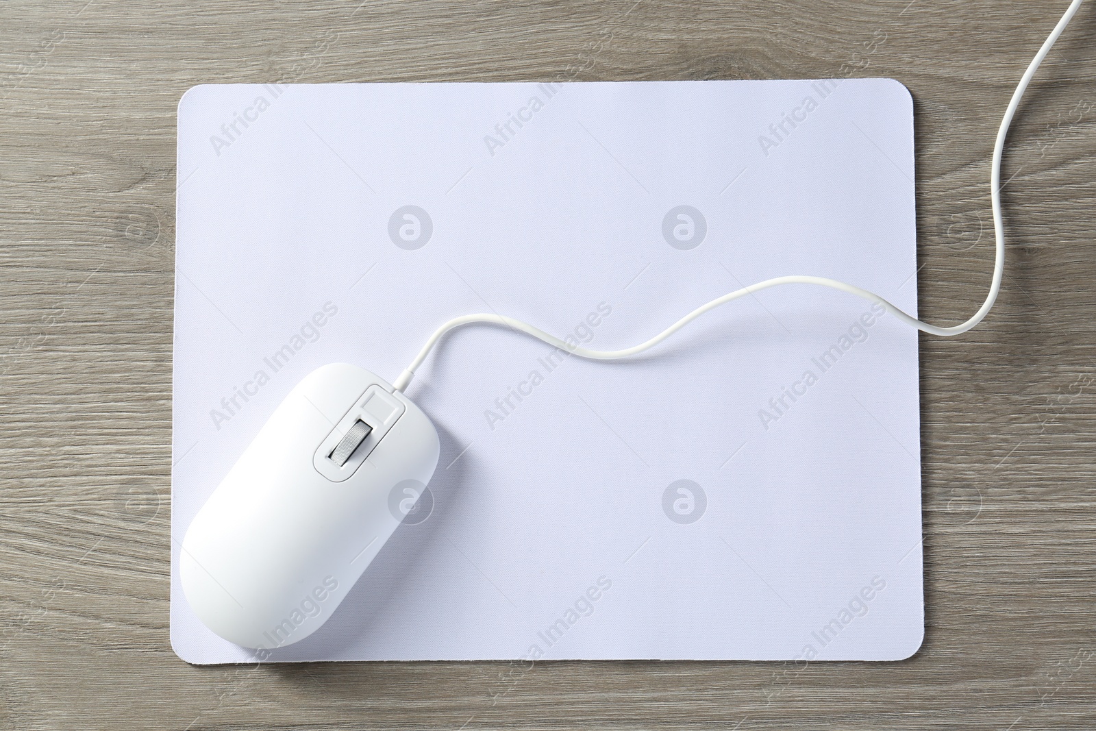 Photo of Wired mouse and mousepad on wooden table, top view