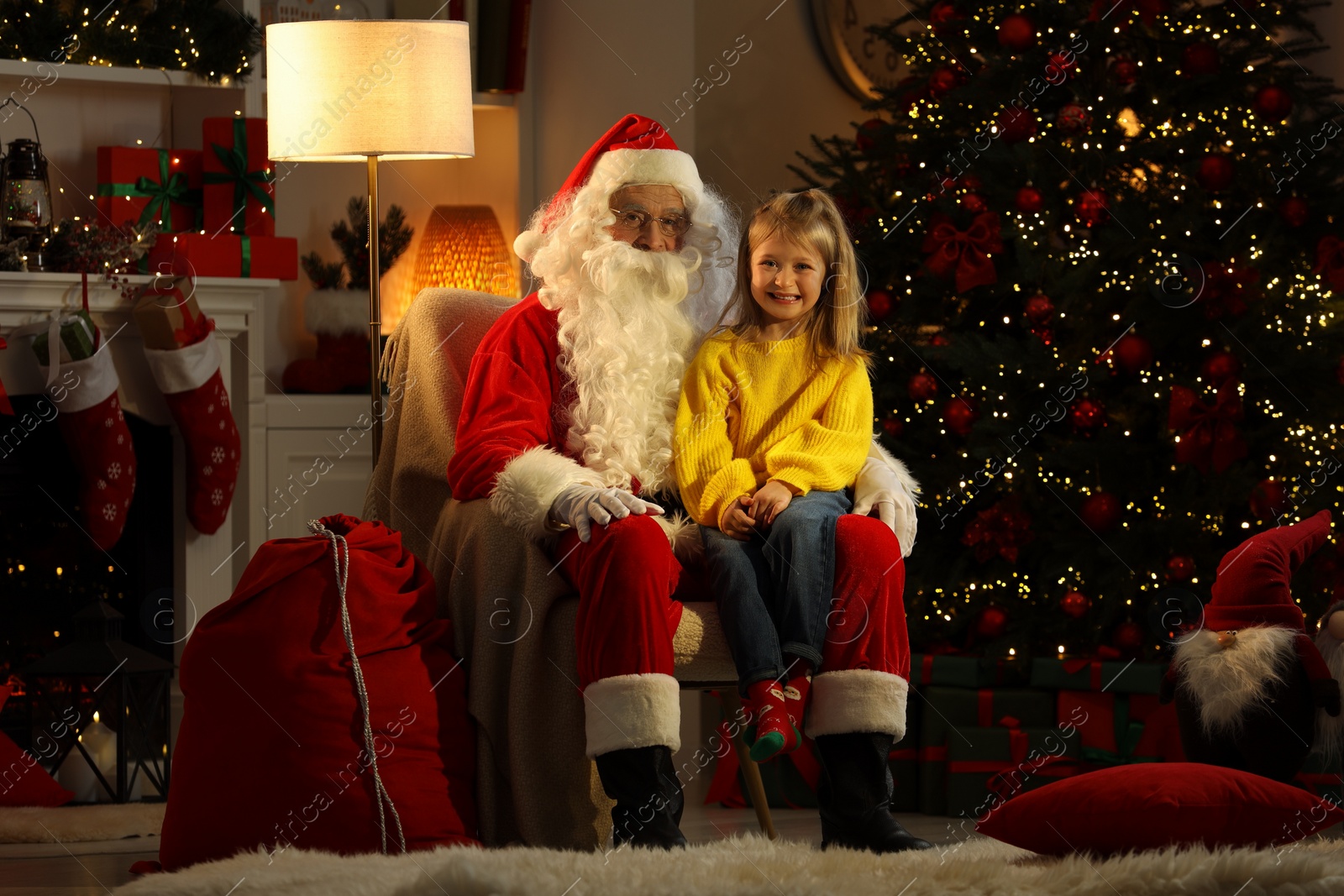 Photo of Merry Christmas. Little girl sitting on Santa's knee at home