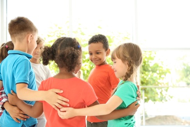 Photo of Little children making circle with hands around each other indoors. Unity concept