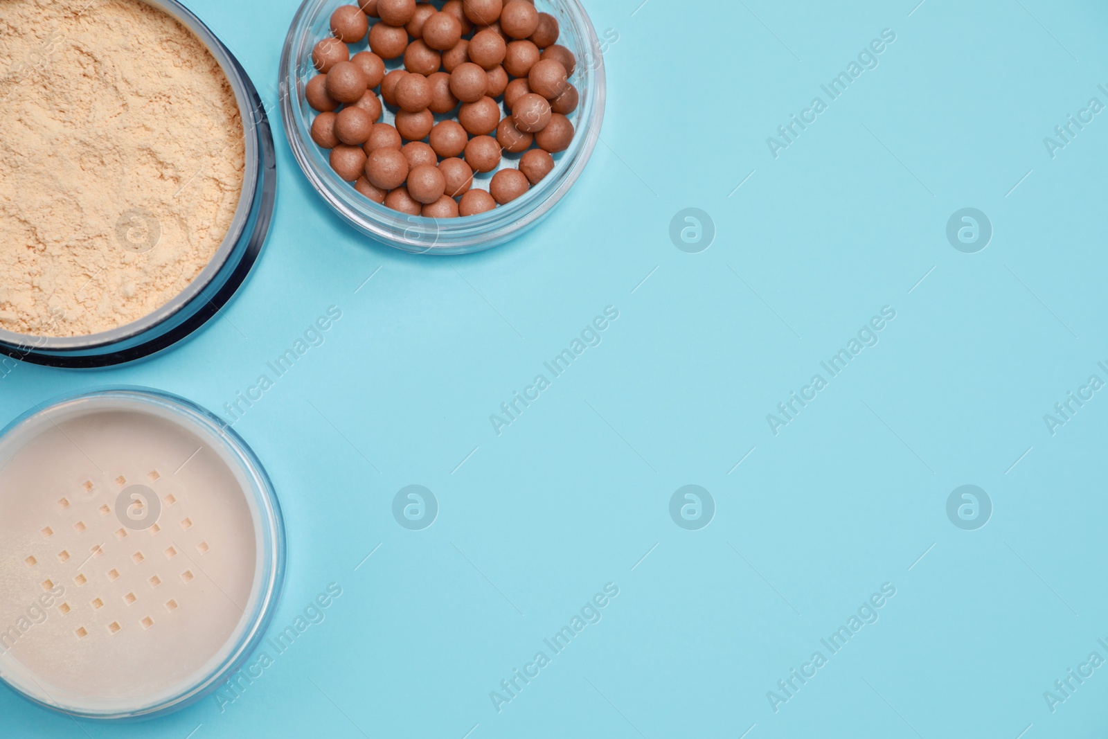 Photo of Different face powders on light blue background, flat lay. Space for text