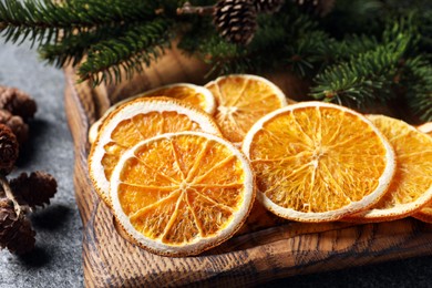 Photo of Dry orange slices, cones and fir tree branches on grey table, closeup