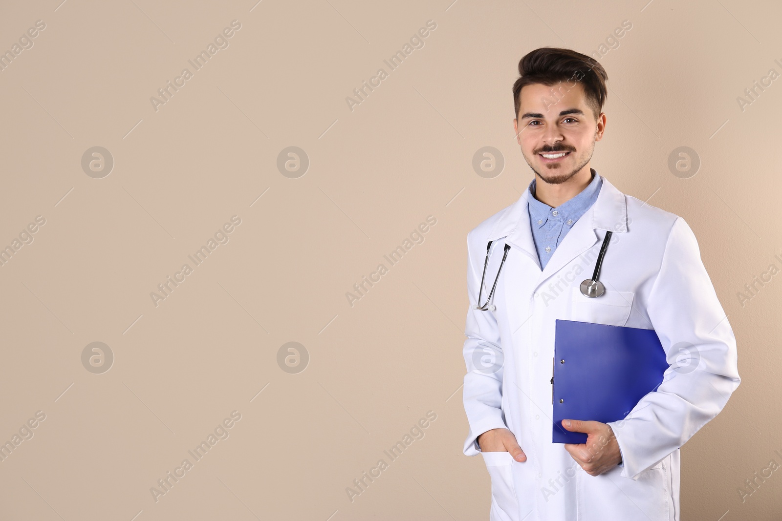 Photo of Young medical student with clipboard on color background. Space for text