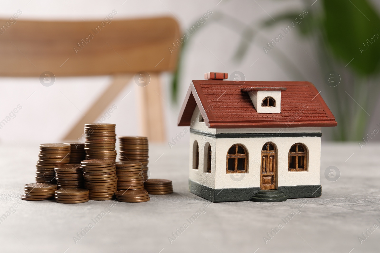 Photo of House model and stacked coins on grey table indoors, closeup