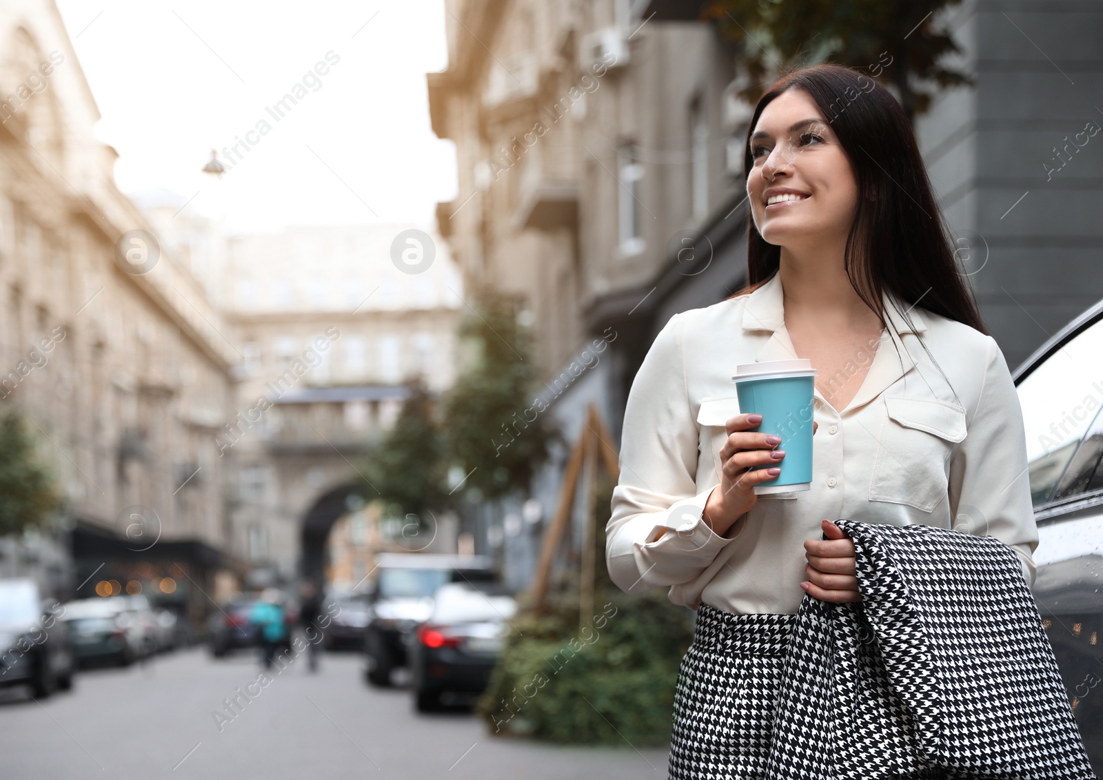 Photo of Beautiful woman in stylish suit with cup of coffee on city street