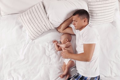 Photo of Father and baby sleeping on bed together, top view. Space for text