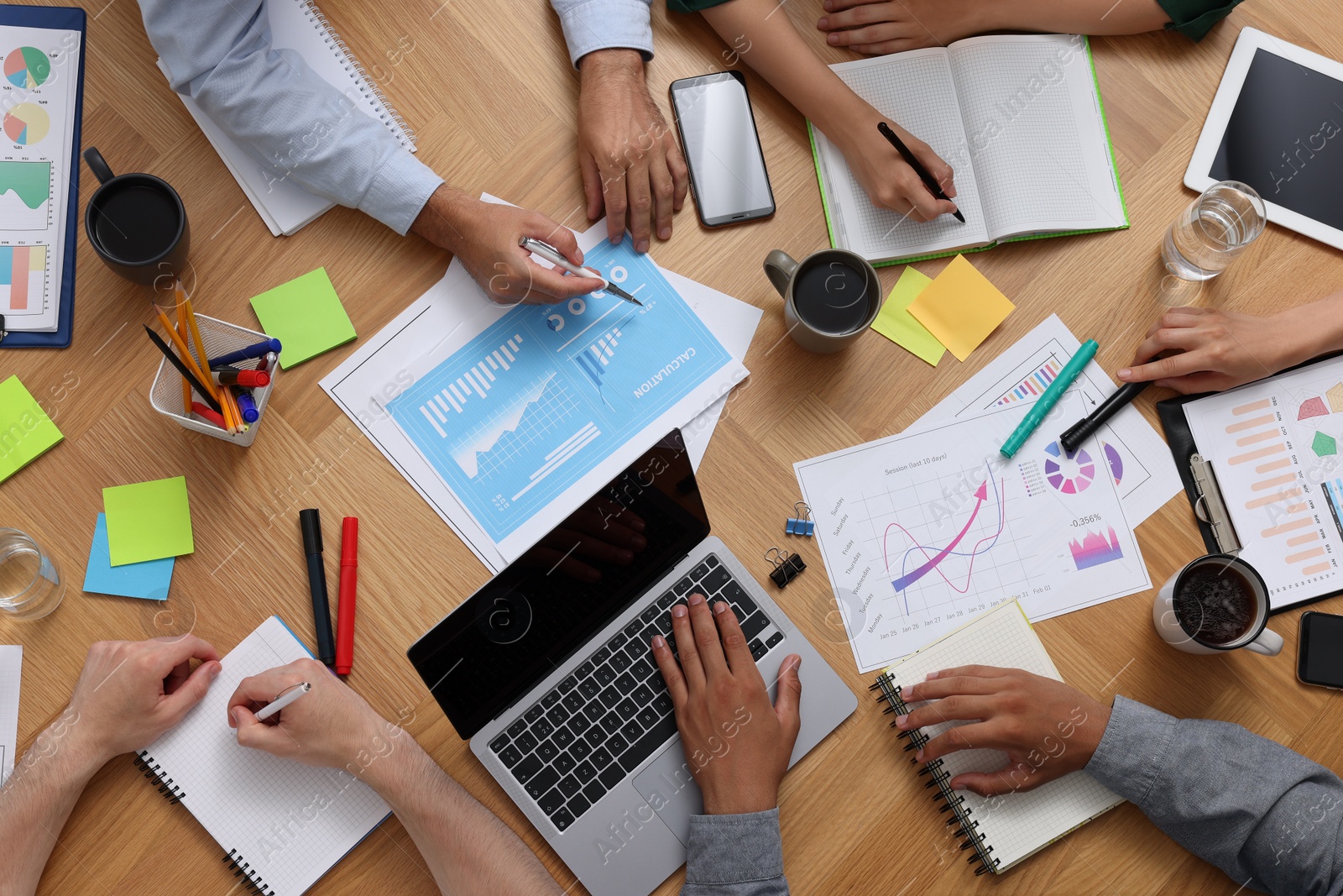 Photo of Team of employees working together at wooden table, top view. Startup project