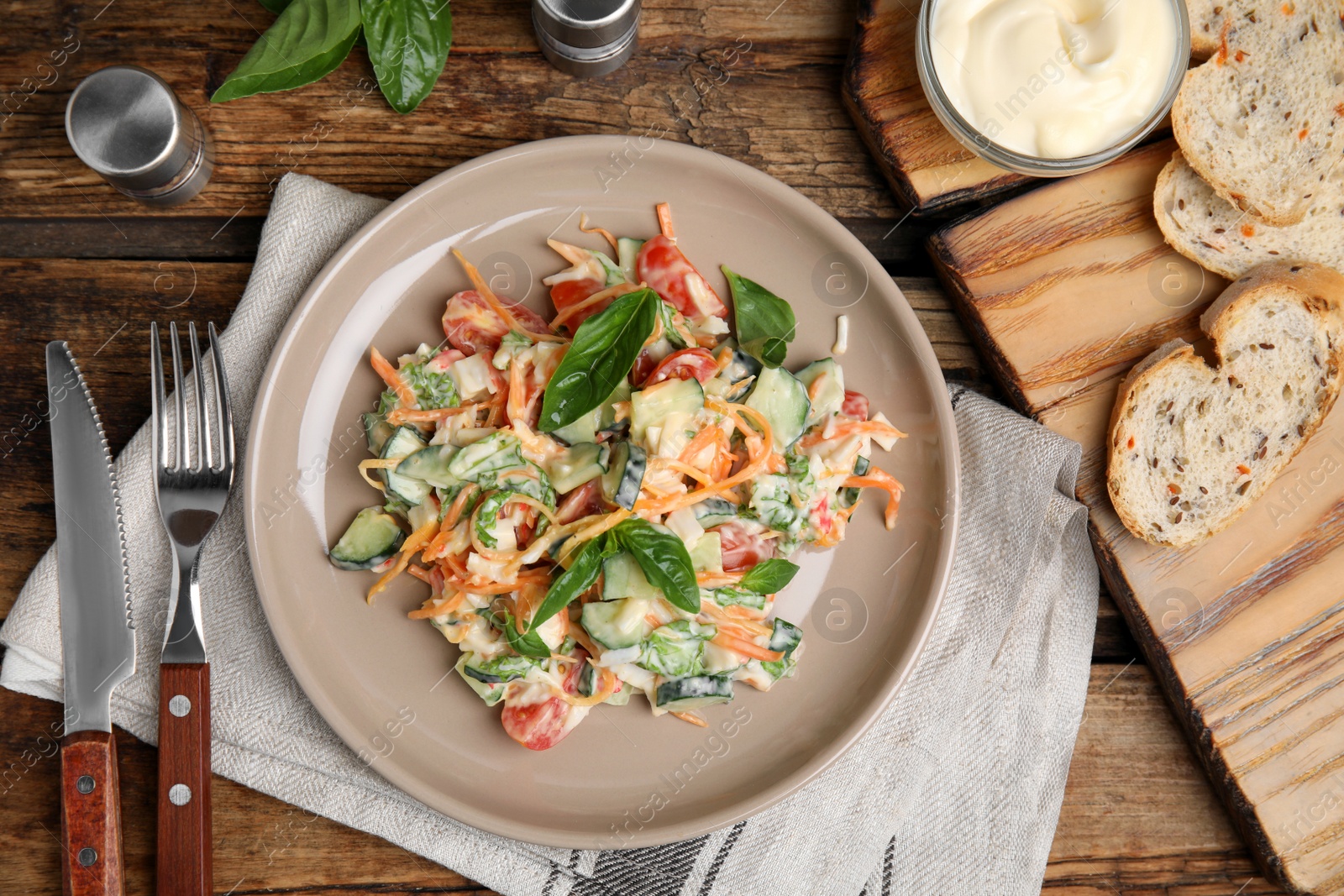 Photo of Delicious salad with mayonnaise served on wooden table, flat lay