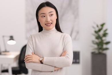 Portrait of smiling businesswoman with crossed arms in office