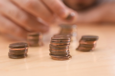 Photo of Stack of coins and blurred man at table, closeup. Counting money