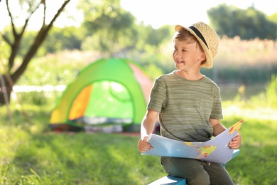 Photo of Little boy with map near tent outdoors. Summer camp