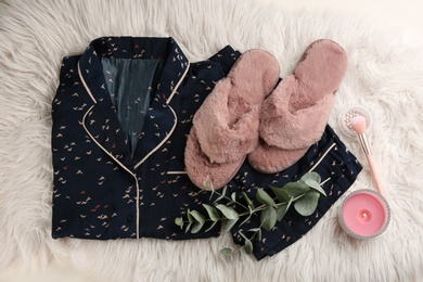 Flat lay composition with house slippers and pajamas on light faux fur