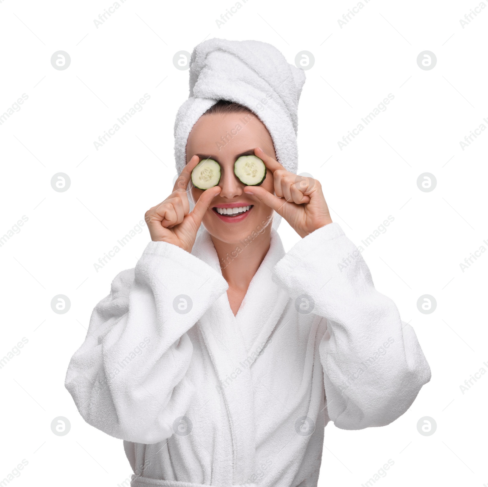 Photo of Beautiful woman in bathrobe covering eyes with pieces of cucumber on white background