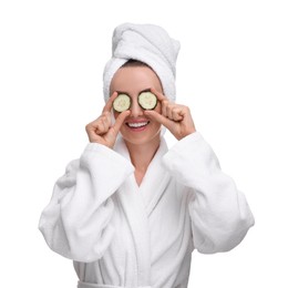 Photo of Beautiful woman in bathrobe covering eyes with pieces of cucumber on white background