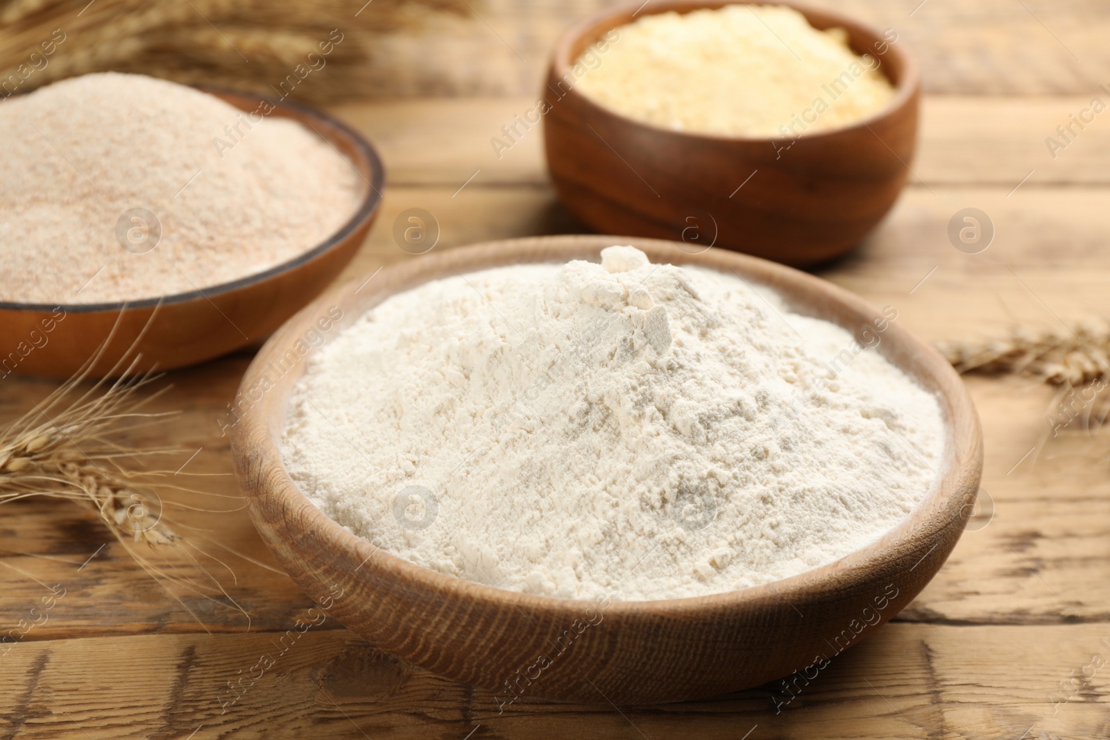 Photo of Wheat flour in bowl on wooden table