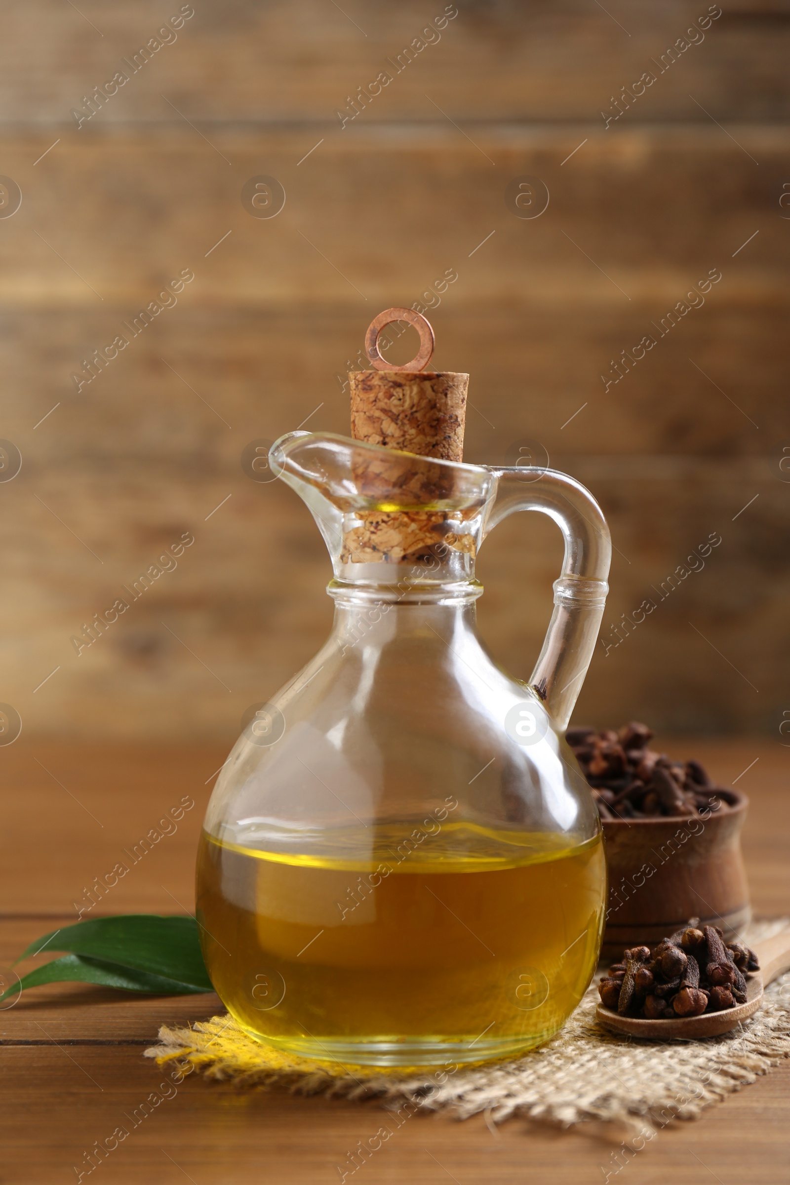 Photo of Essential oil and dried cloves on wooden table