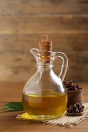 Essential oil and dried cloves on wooden table