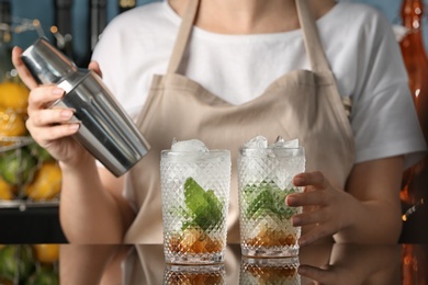 Bartender preparing delicious mint julep cocktail at table