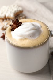 Photo of Cup of delicious eggnog with anise star on wooden table, closeup