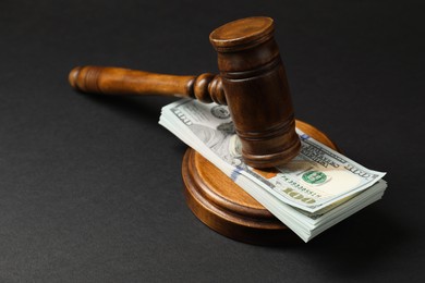 Law gavel with stack of dollars on black table, closeup