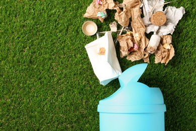 Photo of Trash bin and different garbage on green grass, top view with space for text. Waste recycling concept