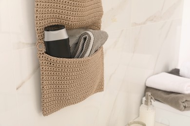 Photo of Knitted organizer hanging on wall in bathroom, closeup