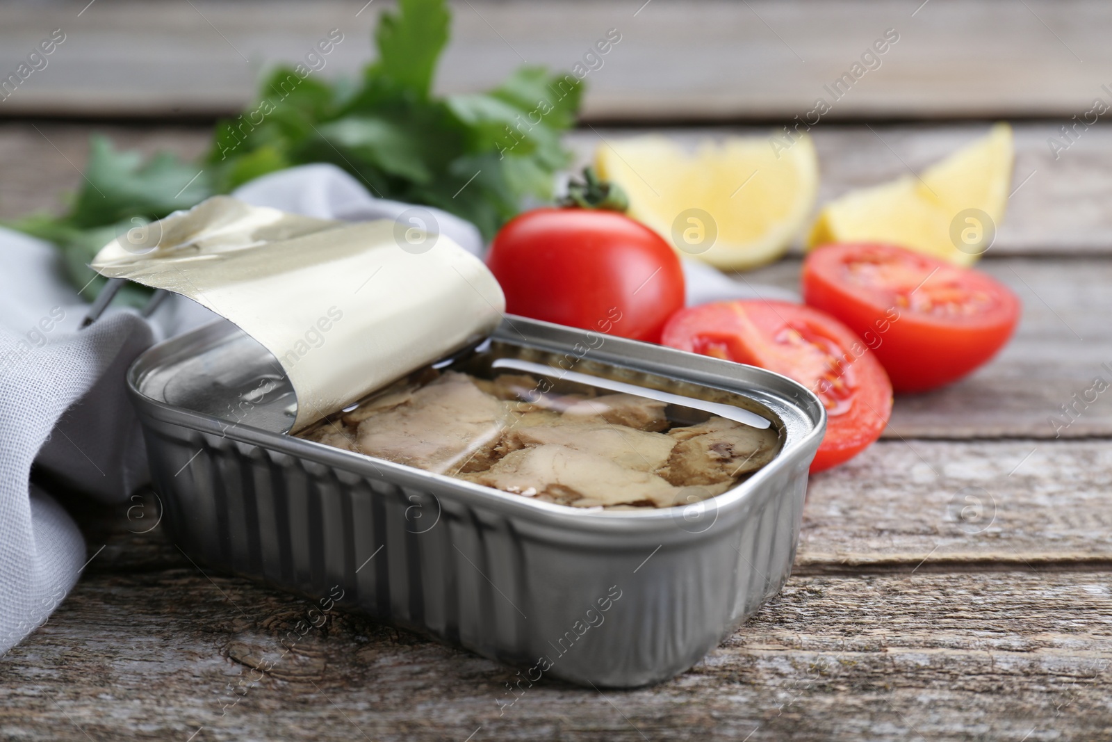 Photo of Open tin can of tasty cod liver on wooden table, closeup